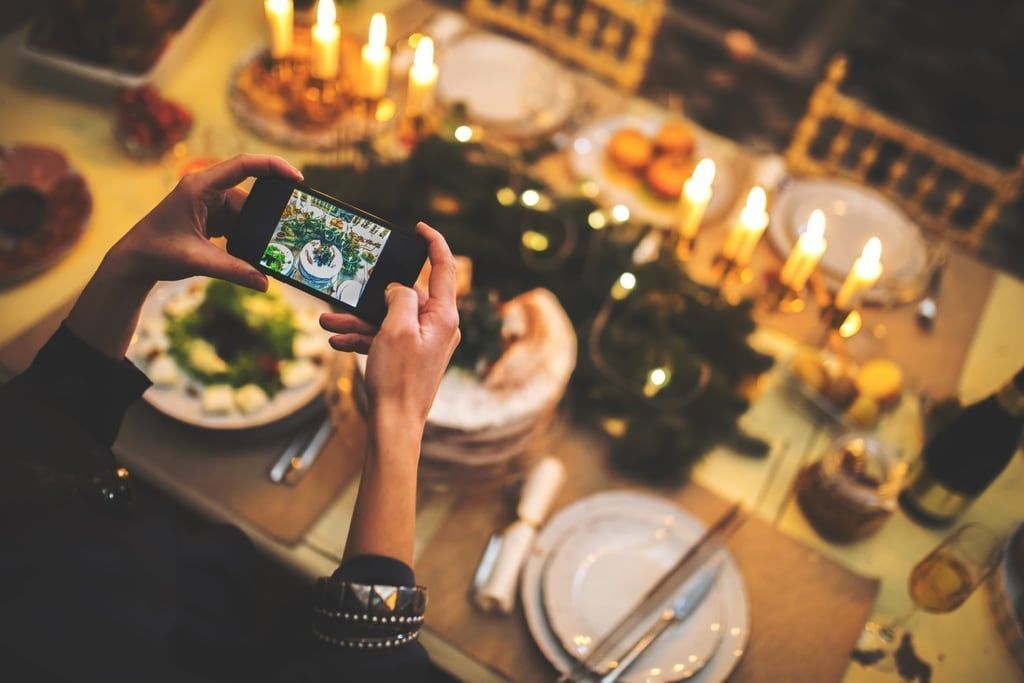 Frau fotografiert Weihnachtstisch mit Smartphone