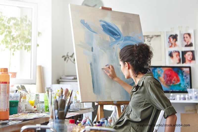 Kreative Frau malt mit Fingern auf Leinwand an Staffelei